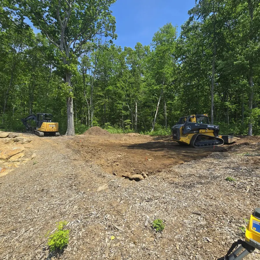 Graded building pad with excavators on site before the underground utility runs go in