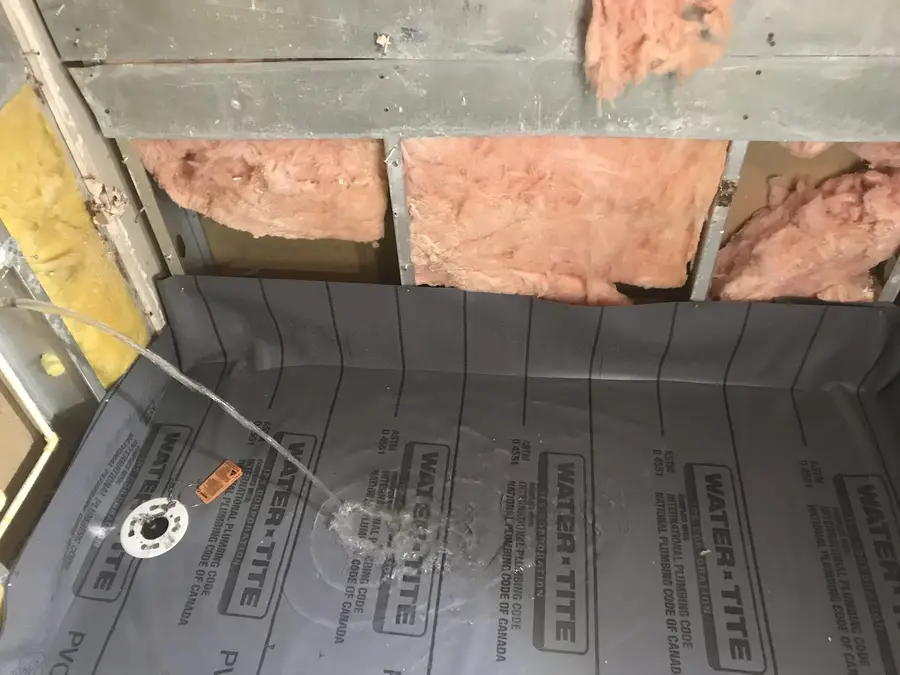 Water heater safety pan fitted into a closet floor before the tank is set, ready for its drain line