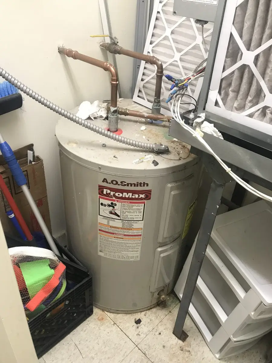 Electric storage water heater installed in a utility alcove with new supply lines run overhead