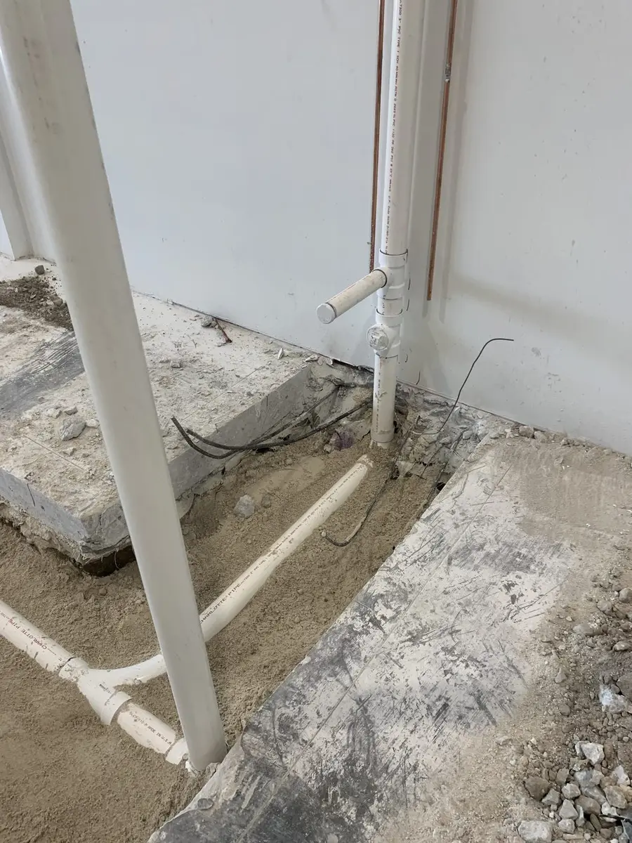 PVC drain lines set at slab level with the stack run up a finished interior wall