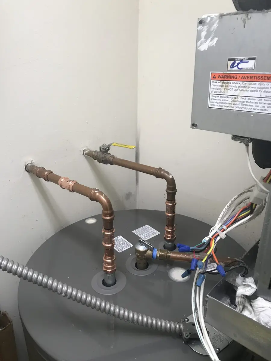 Top of a water heater showing new copper nipples, flexible connectors and a fresh electrical whip